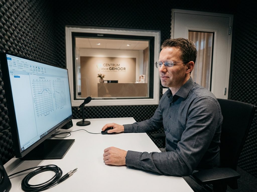 Audiologiste effectuant un test auditif dans une cabine insonorisée d'un centre auditif belge